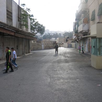 Israelsk soldat går gennem gaden, hvor de palæstinensiske børn leger