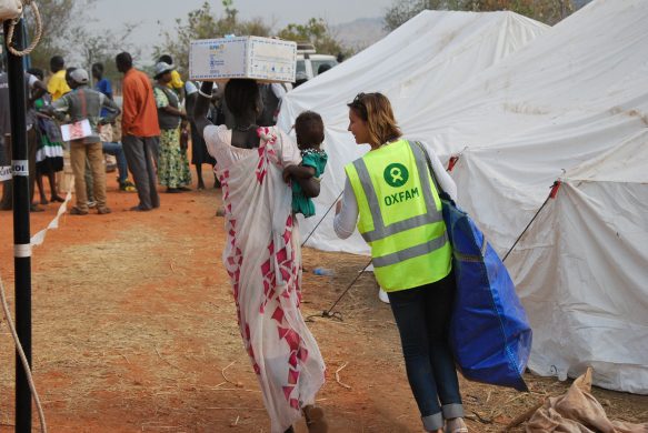 an_oxfam_member_of_staff_helps_to_carry_one_familys_newly_received_non-food_items_home_in_un_house_juba_12046957855
